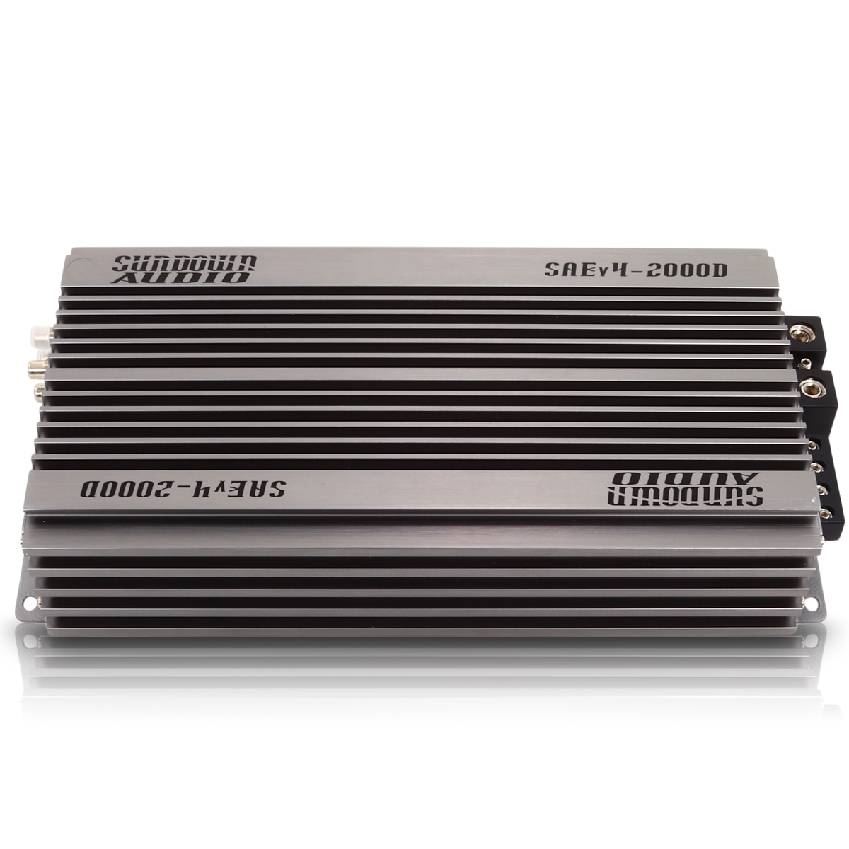 A rectangular Class D car amplifier, the Sundown Audio SAEv4-2000.1D, features a sleek silver finish with black cooling fins and thermal control. It has visible input and output connections on one side and is labeled on the top surface for optimal performance.