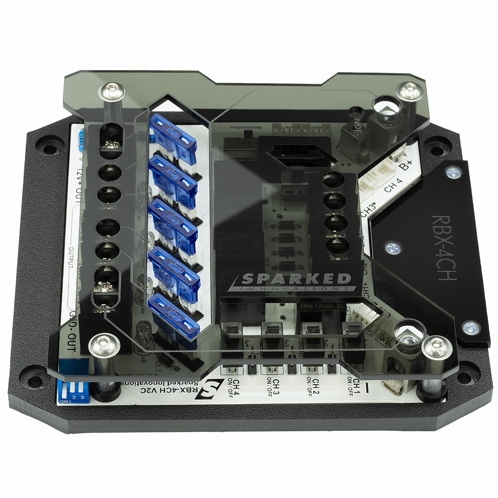 A close-up of a black and transparent electronic device with multiple blue connectors and exposed circuits, labeled SPARKED. The design appears technical, meant for electrical or computer hardware use.