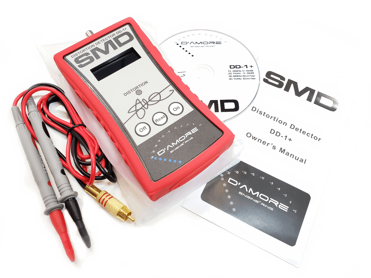 The SMD Distortion Detector Plus (DD-1+) Digital Microcontroller by Steve Meade Designs is displayed with a pair of test probes, a CD, an instruction manual, and a signed card. The brand SMD is visible on both the device and accompanying materials, making it an ideal tool for setting audio amplifier gain.