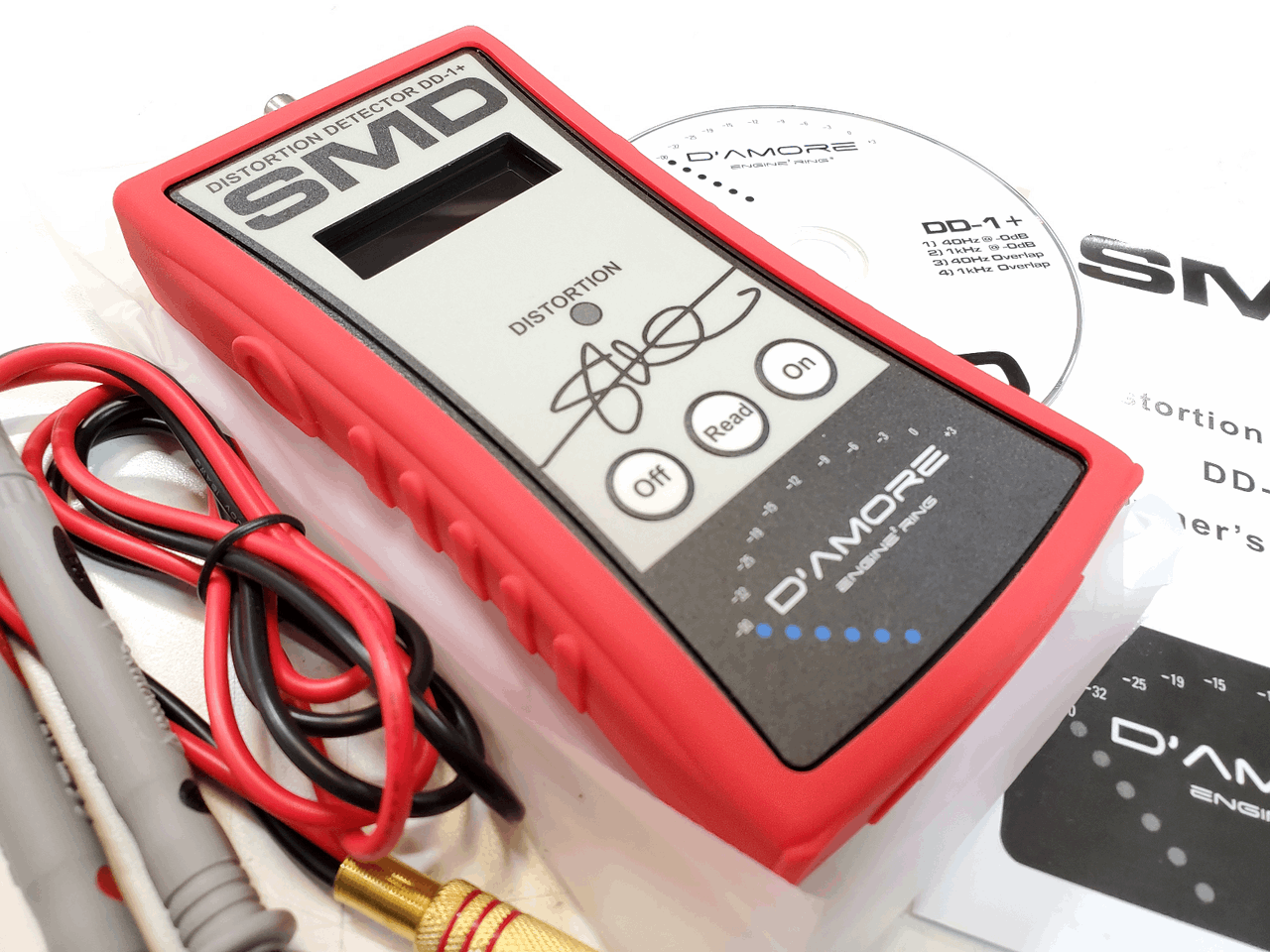 A close-up of the SMD Distortion Detector Plus (DD-1+) Digital Microcontroller by Steve Meade Designs, a sophisticated gain setting tool. The device features a digital screen and buttons labeled Off, Read, and On, all encased in a red protective sleeve. Accessories include test leads and a CD for enhanced audio amplifier testing.