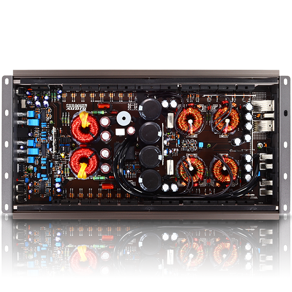 Close-up view of the Sundown Audio SALT-2 2000W Class D amplifier circuit board with exposed electronic components, including capacitors, coils, and resistors. The board features dense wiring and intricate arrangements within a metallic casing.