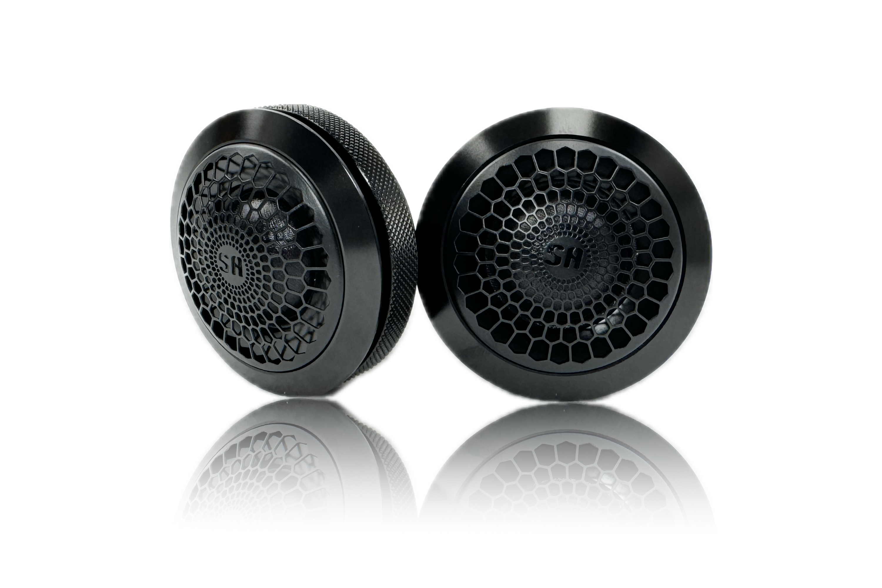 Two Sundown Audio SA-Series SA-1T 1" silk dome tweeters with honeycomb-patterned grilles and a sleek black finish, gently reflecting on a white surface. The tweeters are positioned side by side, highlighting their modern and sophisticated design.